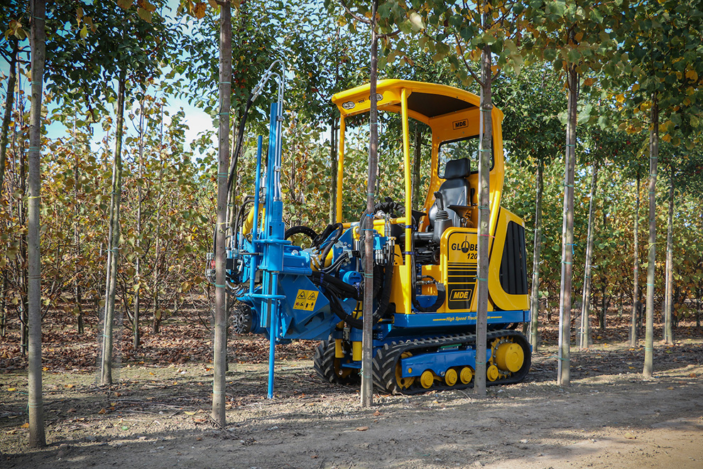 Landbouwmachines in werking bij een kwekerij, omringd door bomen, vertegenwoordigen de diensten van Agro-NL Consult Solutions.